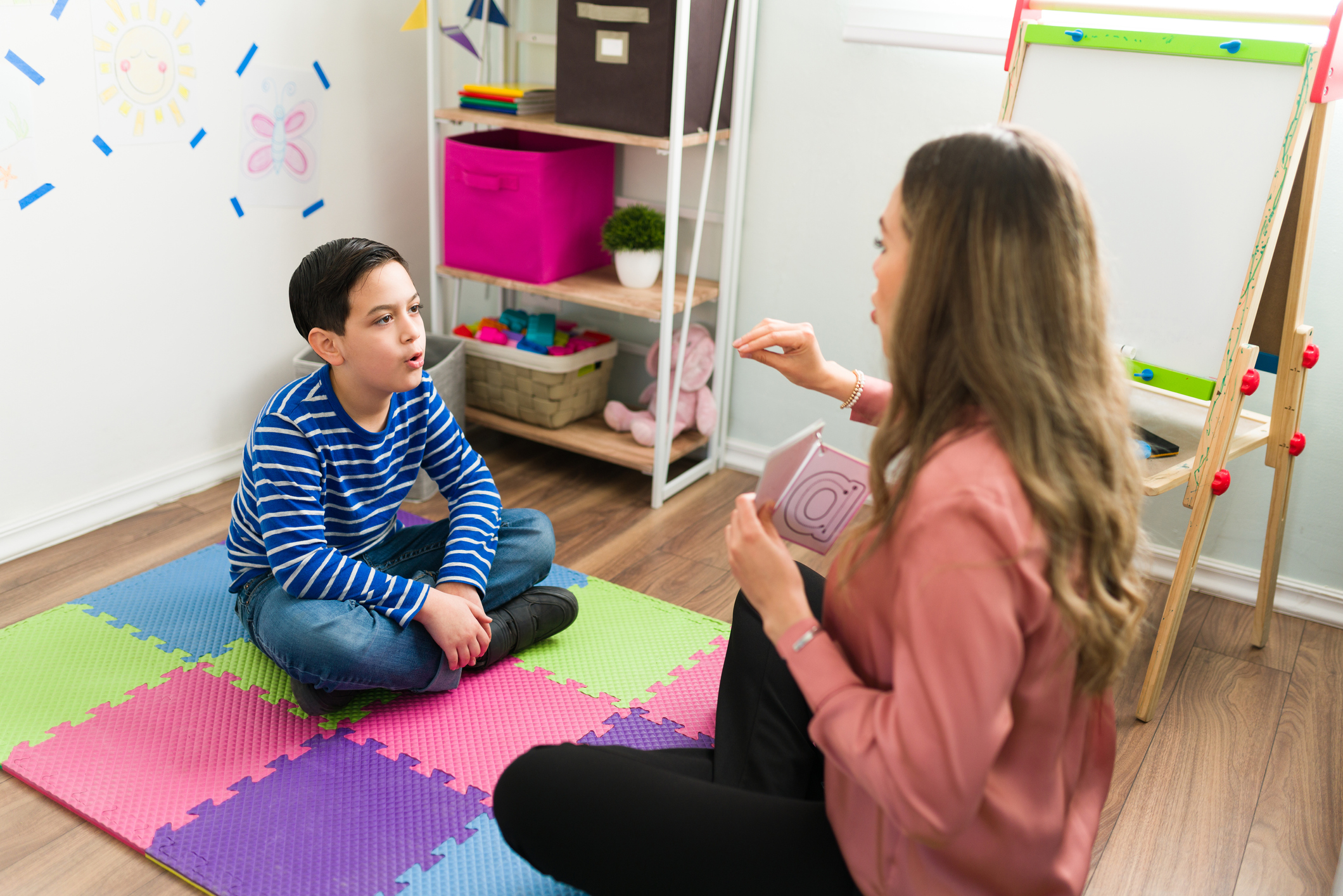 Caucasian boy repeating and making sounds together with a female therapist during a speech and language therapy session